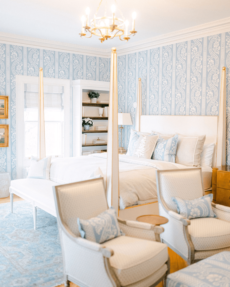 Bright and airy bedroom featuring a four-poster bed, elegant decor, and light blue wallpaper.