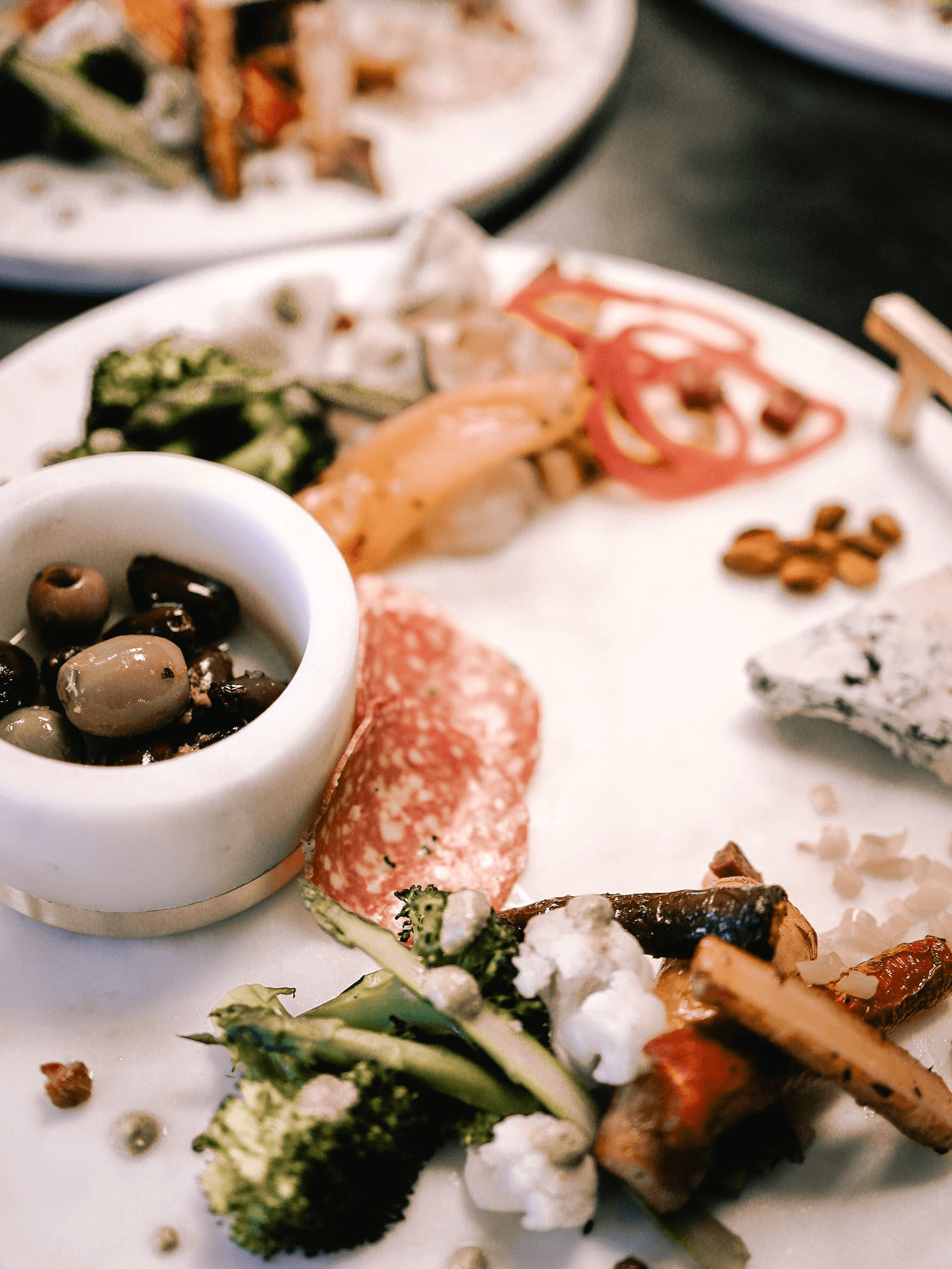 A plate featuring a variety of olives, sliced salami, assorted vegetables, and cheese.